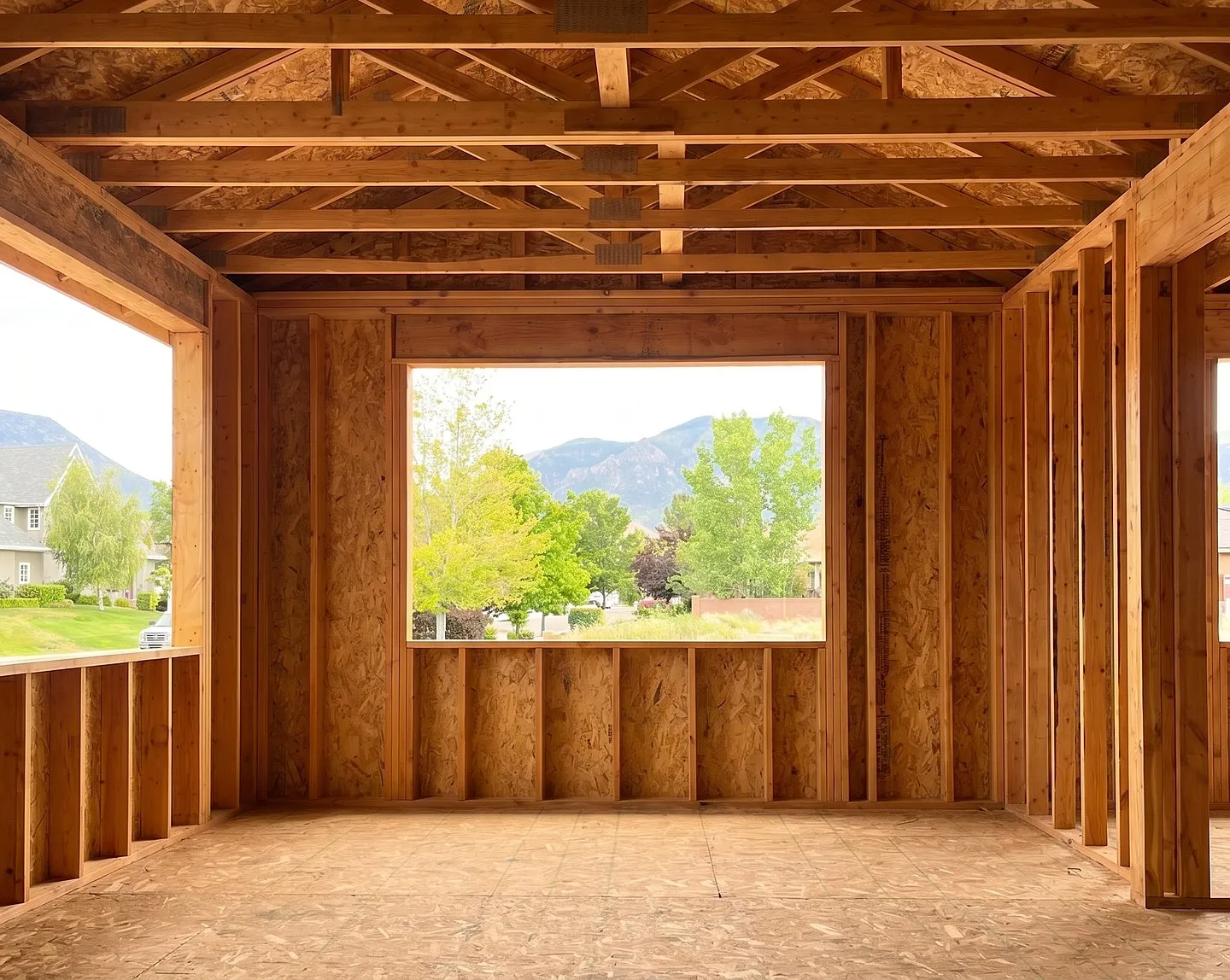 A room addition framed out in stud and truss, the rough window opening looking through to the red hills above Cedar City
