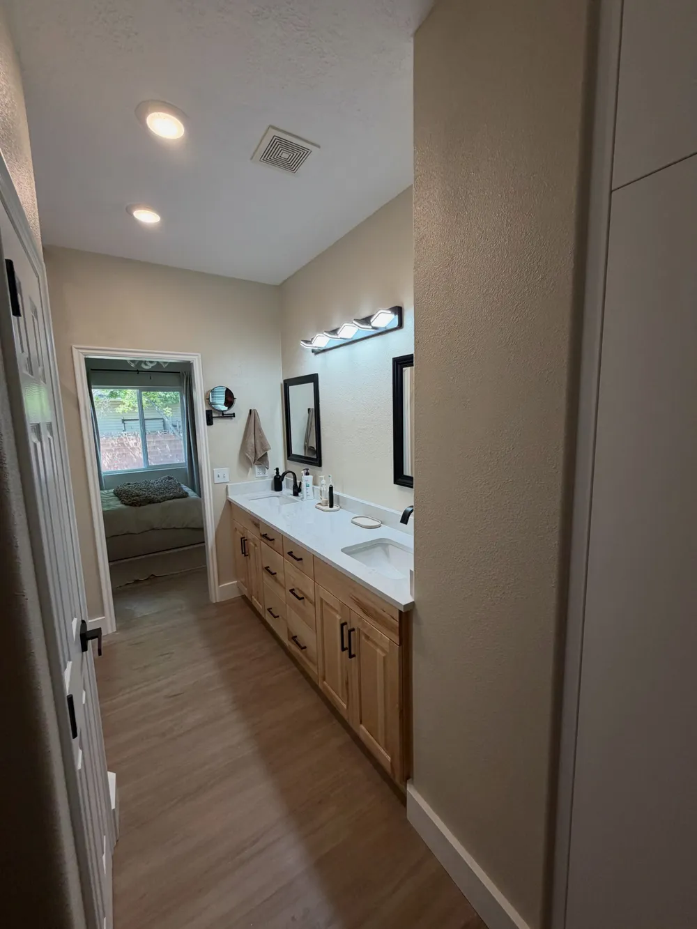 The finished master bathroom: a lengthened double vanity with quartz top, framed mirrors and new plank flooring