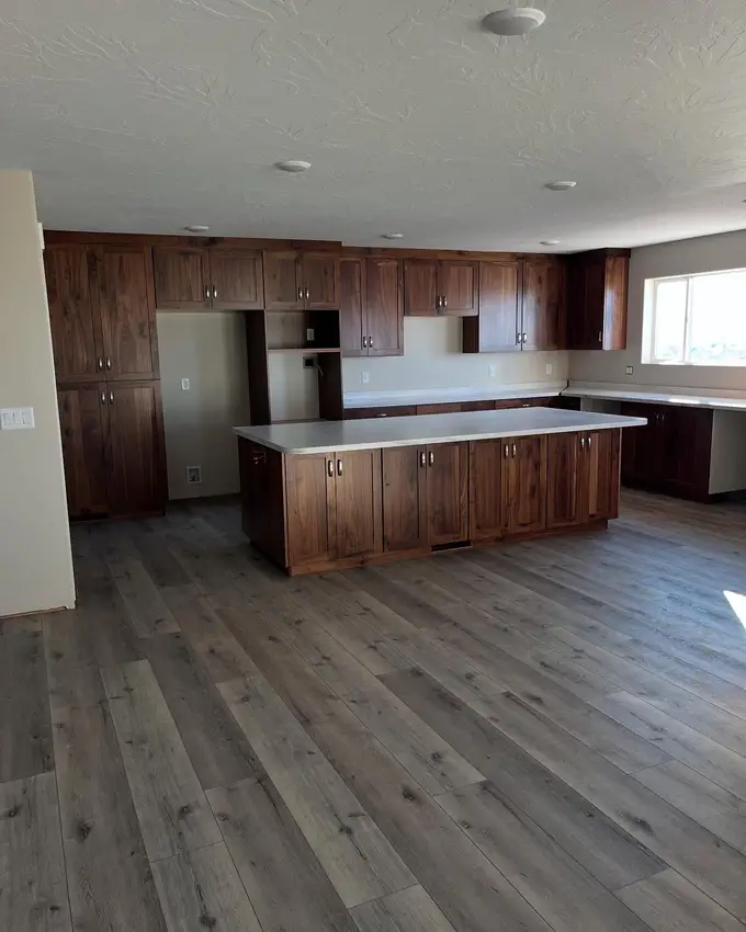 A finished kitchen in walnut: full-height cabinets, a long island with a quartz top and wide plank flooring